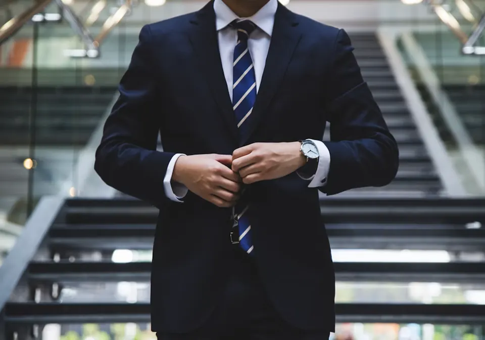 A business leader in a suit fastening a jacket