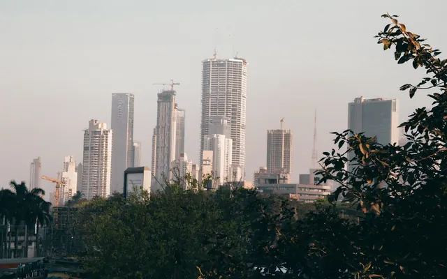 Mumbai high-rise towers seen across trees on a hazy day.